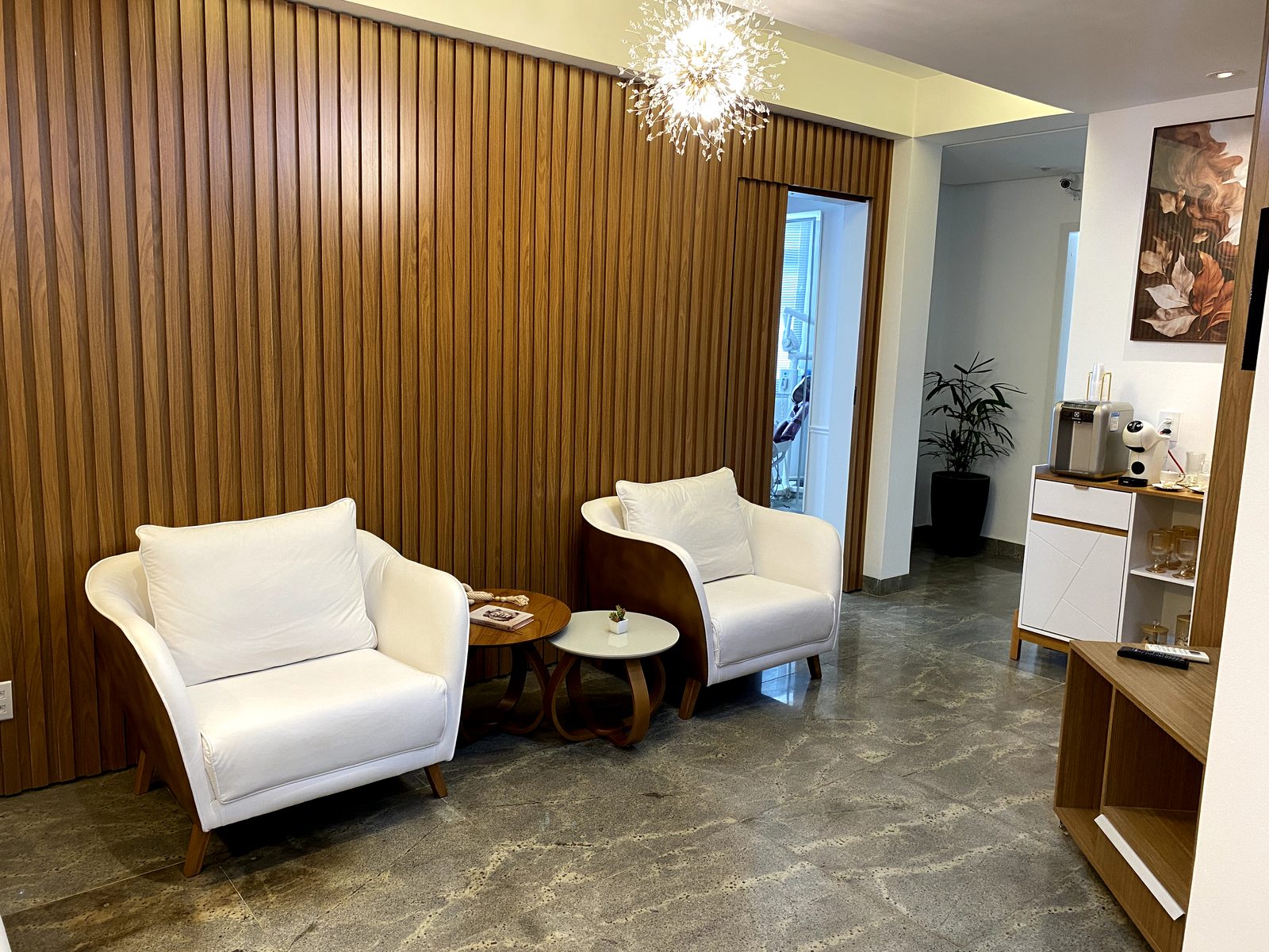 Recepção com poltronas brancas e painel ripado de madeira